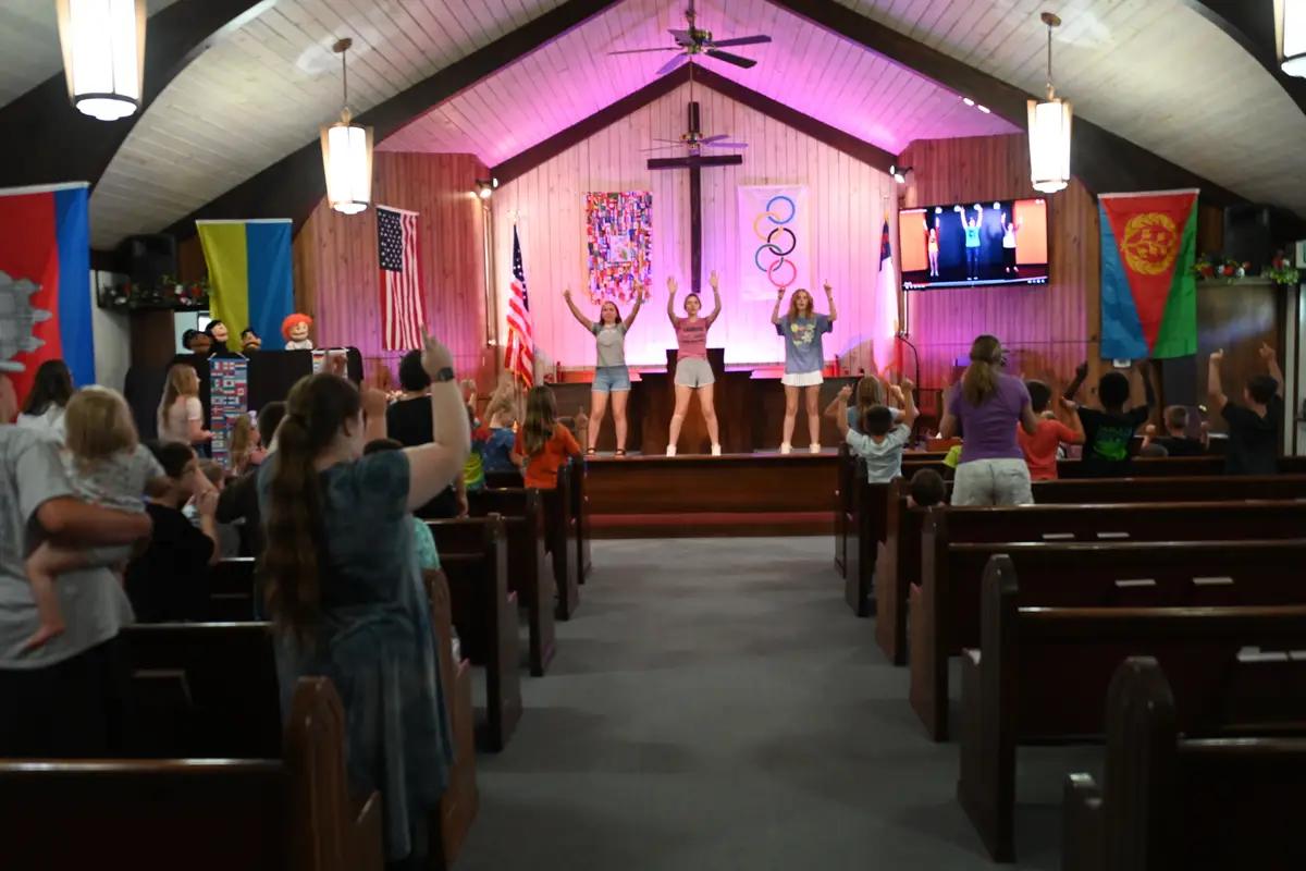 Inside the chapel — wooden vaulted ceiling, pews, and the flags of the nations along the walls